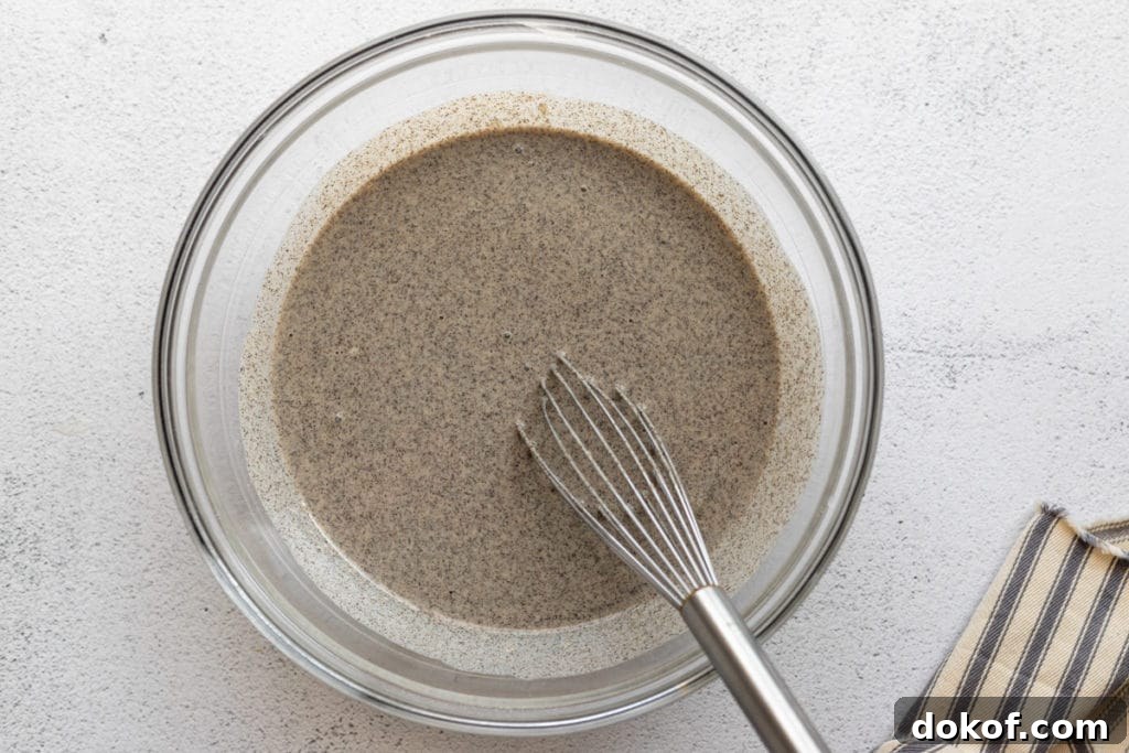 Process shot showing the buckwheat crepes batter in a bowl with a whisk.