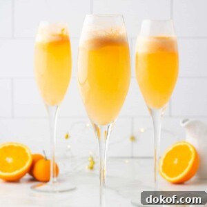 three orange sherbet mimosa mocktails in champagne flutes