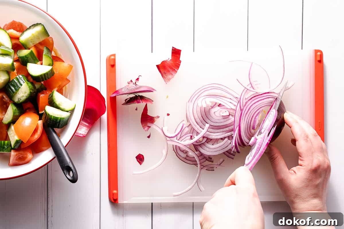 onion being sliced thinly on cutting board