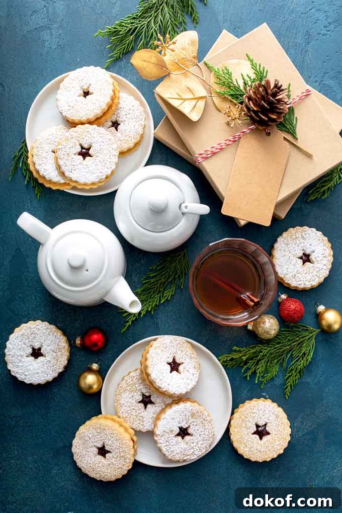 Classic Linzer Cookies Recipe: How to Make Austrian Jam Sandwich Cookies 4 top view of linzer cookies on white plates, next to a white kettle, a white sugar bowl and christmas gifts