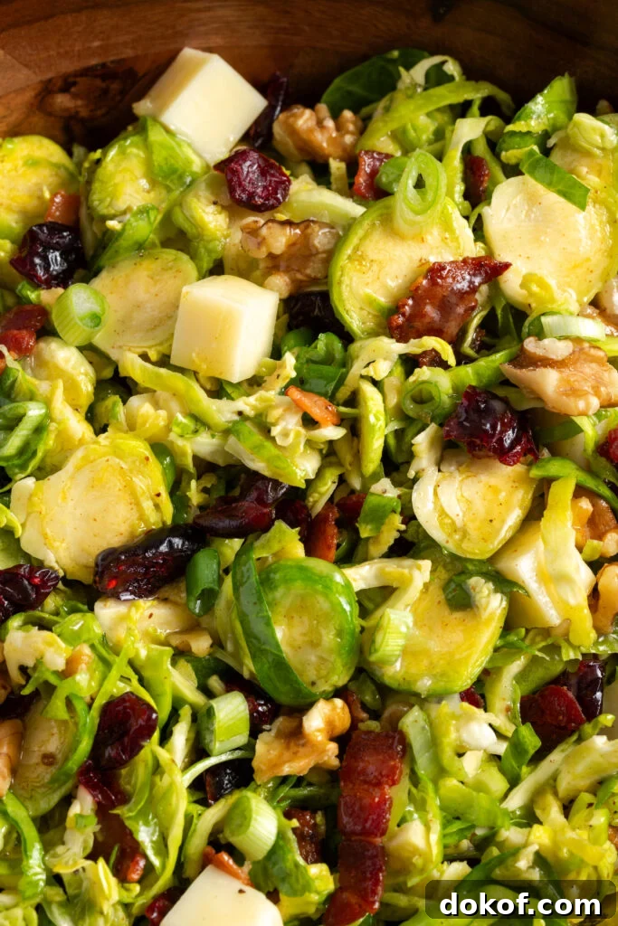 Citrus-Shaved Brussels Sprout Salad with Toasted Almonds 11 closeup shot on the tossed shaved brussel sprouts salad in a wooden bowl.