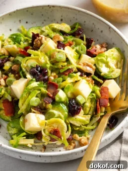 closeup 45 degree angle shot of a serving of brussel sprout salad with a gold fork.