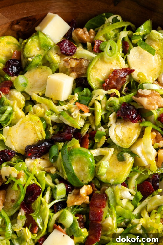 Citrus-Shaved Brussels Sprout Salad with Toasted Almonds 4 closeup shot on the tossed shaved brussels sprouts salad in a wooden bowl.