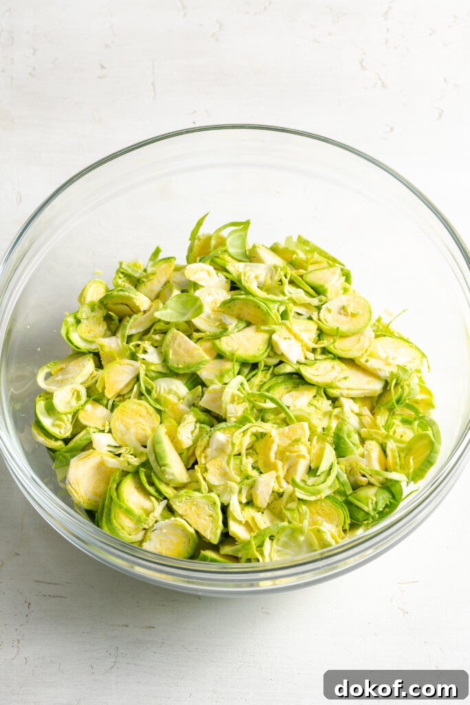 Citrus-Shaved Brussels Sprout Salad with Toasted Almonds 6 plain raw shaved brussels sprouts in a clear mixing bowl.
