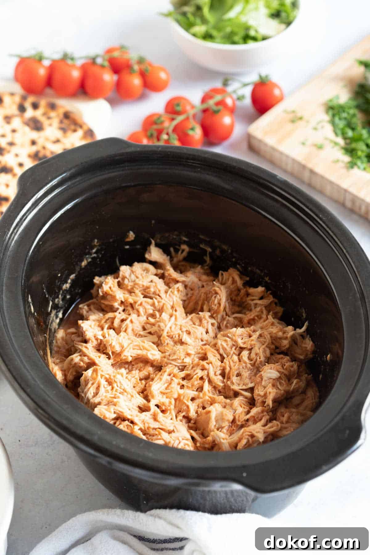 Slow cooker BBQ pulled chicken in a black slow cooker basin.