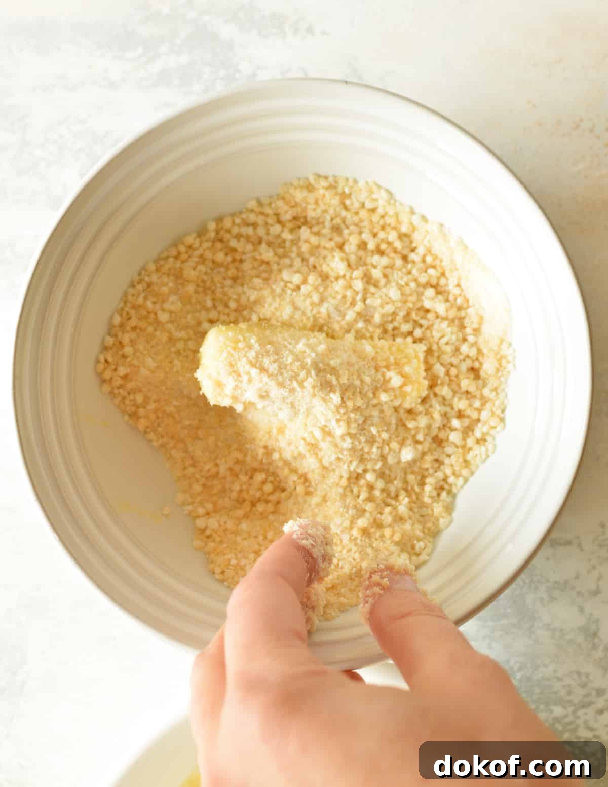 a cheese stick in a bowl of gluten free breadcrumbs