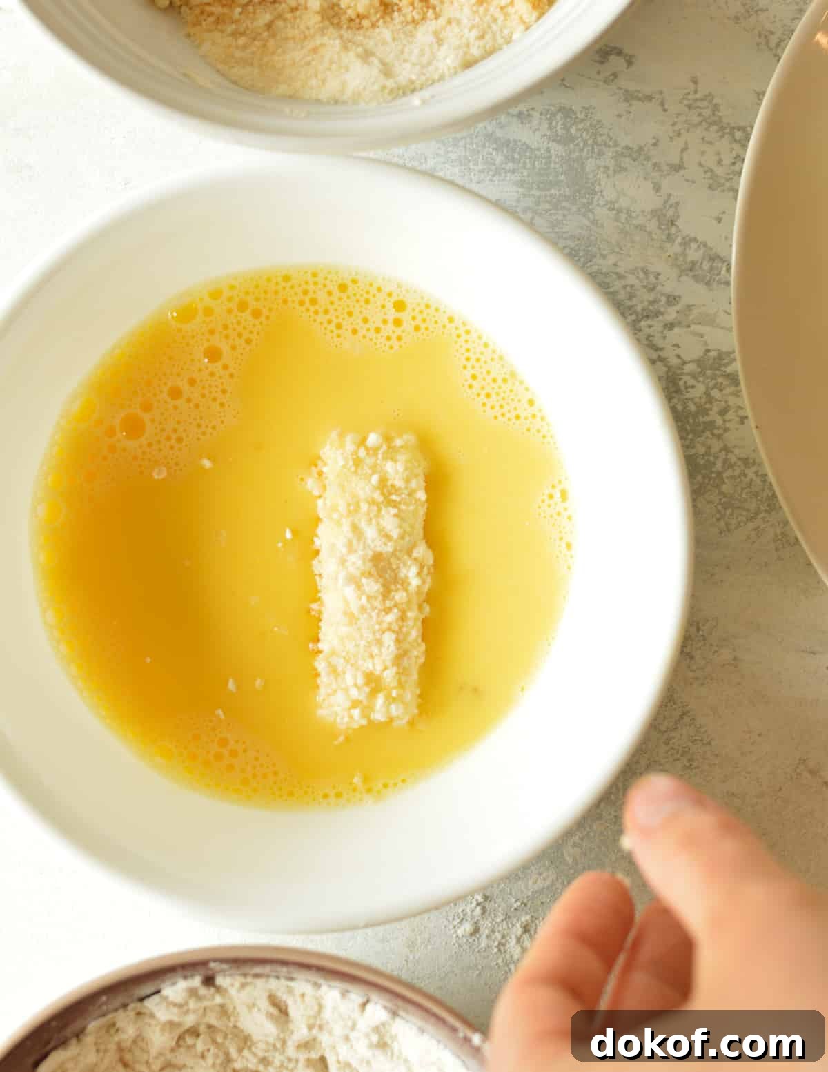 a coated cheese stick in a bowl of egg