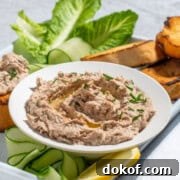 A bowl of tuna pate surrounded by toasted baguette, cucumber ribbons and lettuce.