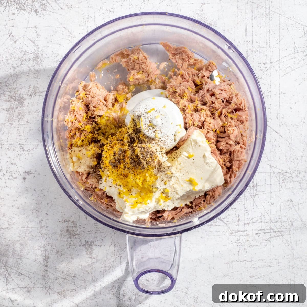 The unblended ingredients for tuna pate in the bowl of a food processor.