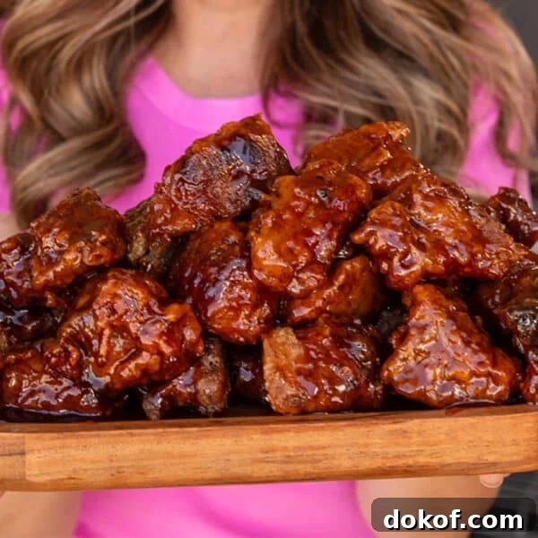 A closeup shot of a wooden platter of battered and sauced brisket cubes.