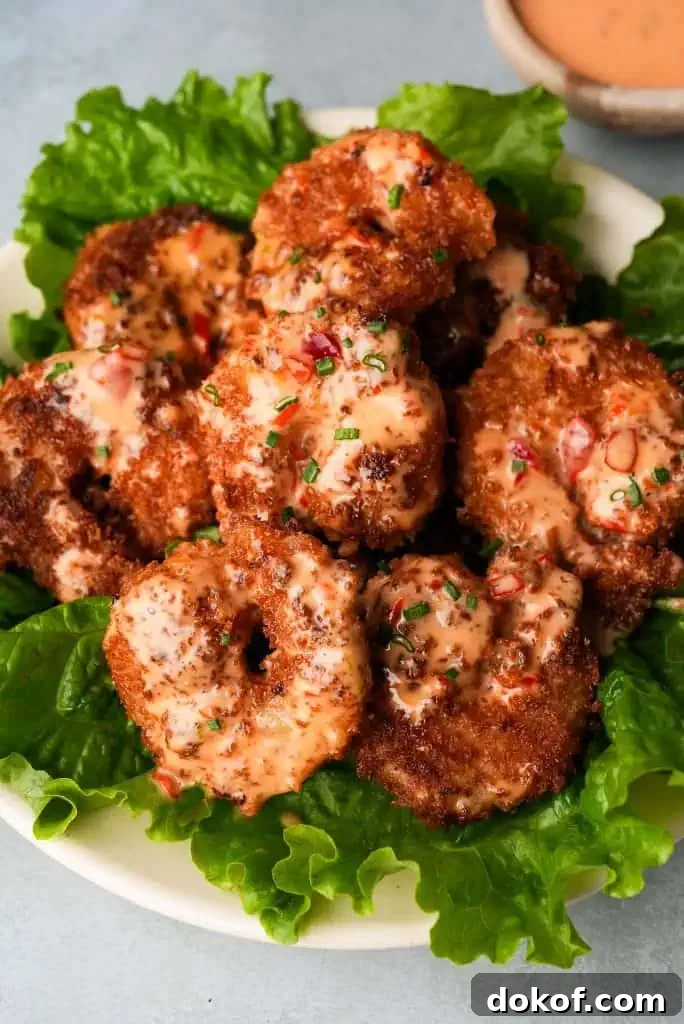 fried shrimp sauce Close up view of bang bang shrimp on a bed of lettuce.