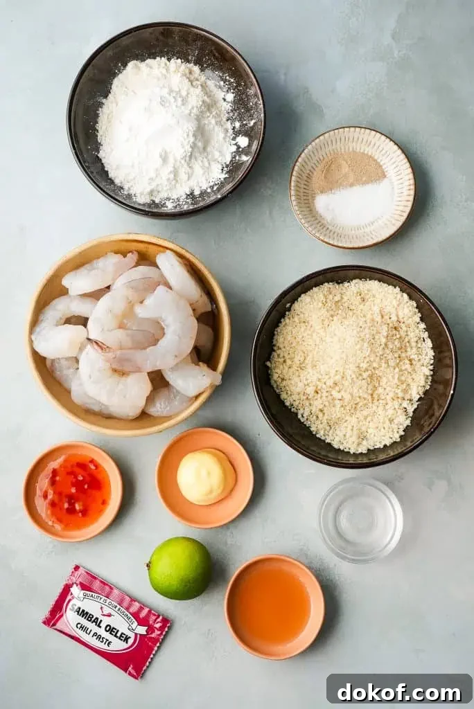 bang bang shrimp ingredients Raw peeled shrimp, panko breadcrumbs, flour, seasonings, eggs, chili sauce, mayonnaise, lime, honey, and sambal oelek are arranged in small bowls on a light surface for bang bang shrimp.