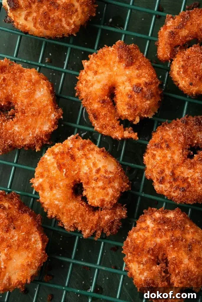 what is bang bang shrimp Breaded shrimp with a deep golden crust rest on a wire rack, showing an evenly fried exterior with crisp, textured coating.