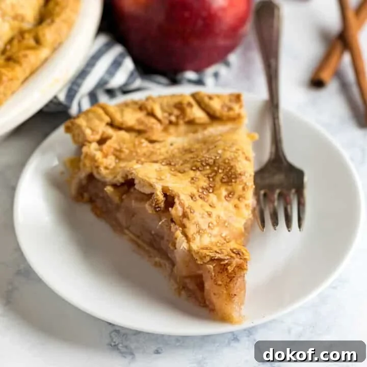 A slice of bourbon apple pie with a fork on the plate.