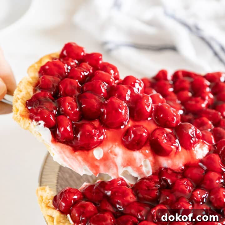 A piece of cherry cheese pie being pulled up from the rest of the pie.