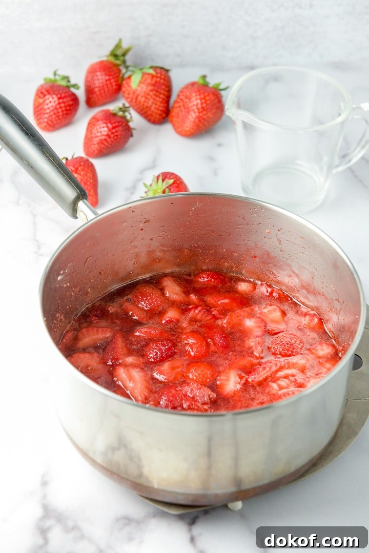 The fruit sauce cooked in the pan with strawberries in the background