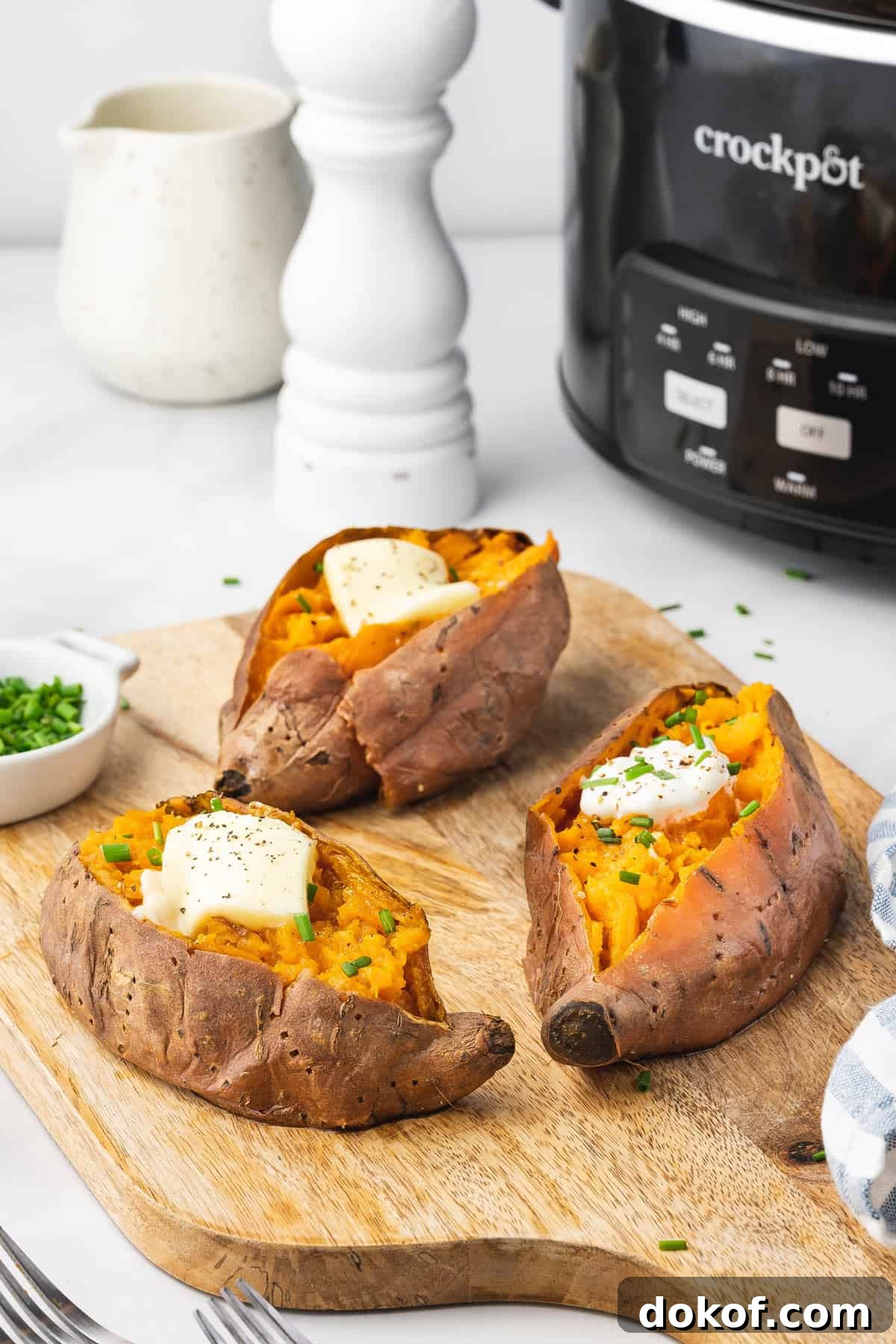 Tender Slow Cooker Sweet Potatoes for Simple Weeknight Meals 3 Three slow cooker sweet potatoes with butter and chives on top.