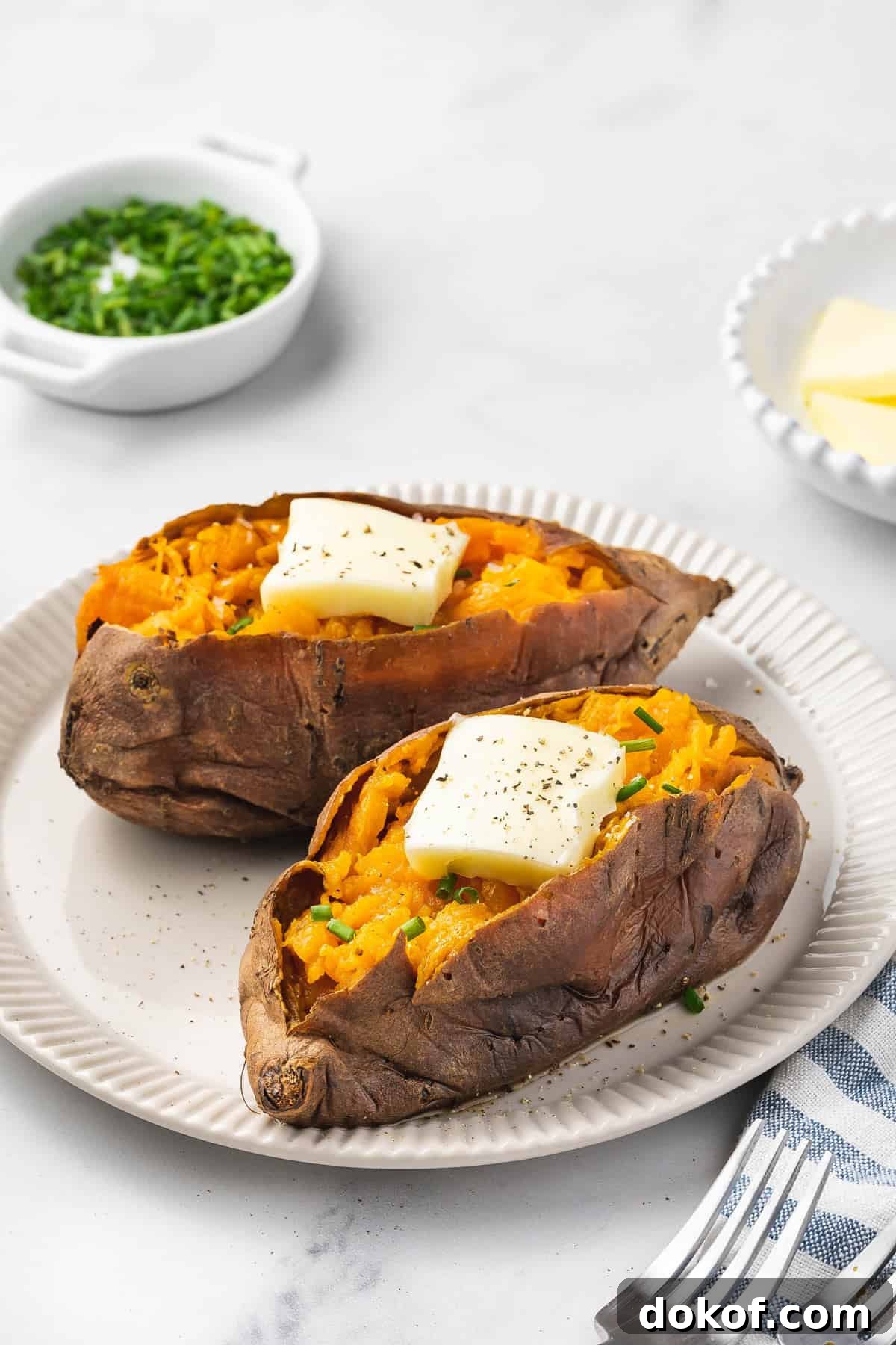 Tender Slow Cooker Sweet Potatoes for Simple Weeknight Meals 8 A plate with two slow cooker sweet potatoes with butter and chives on top.