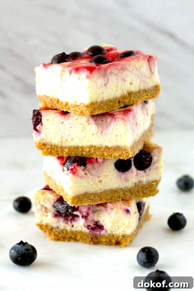 Berry Swirl Cheesecake Bars — Luscious No-Bake Dessert Recipe 2 A stack of berry swirl cheesecake bars on a white kitchen surface.