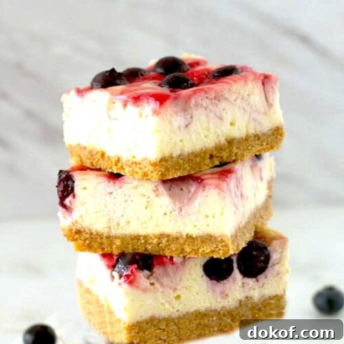 Berry Swirl Cheesecake Bars — Luscious No-Bake Dessert Recipe 5 Three Berry Swirl Cheesecake Bars stacked up on a table.