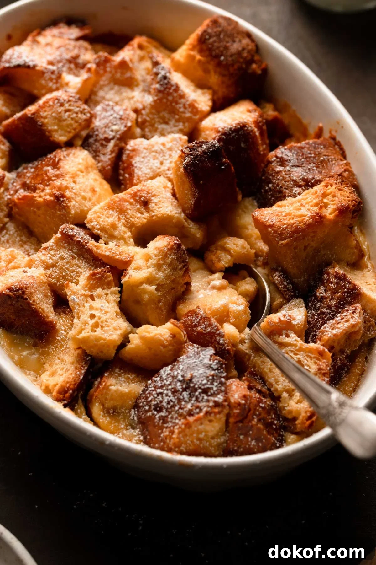 Bread pudding in a dish with a spoon.