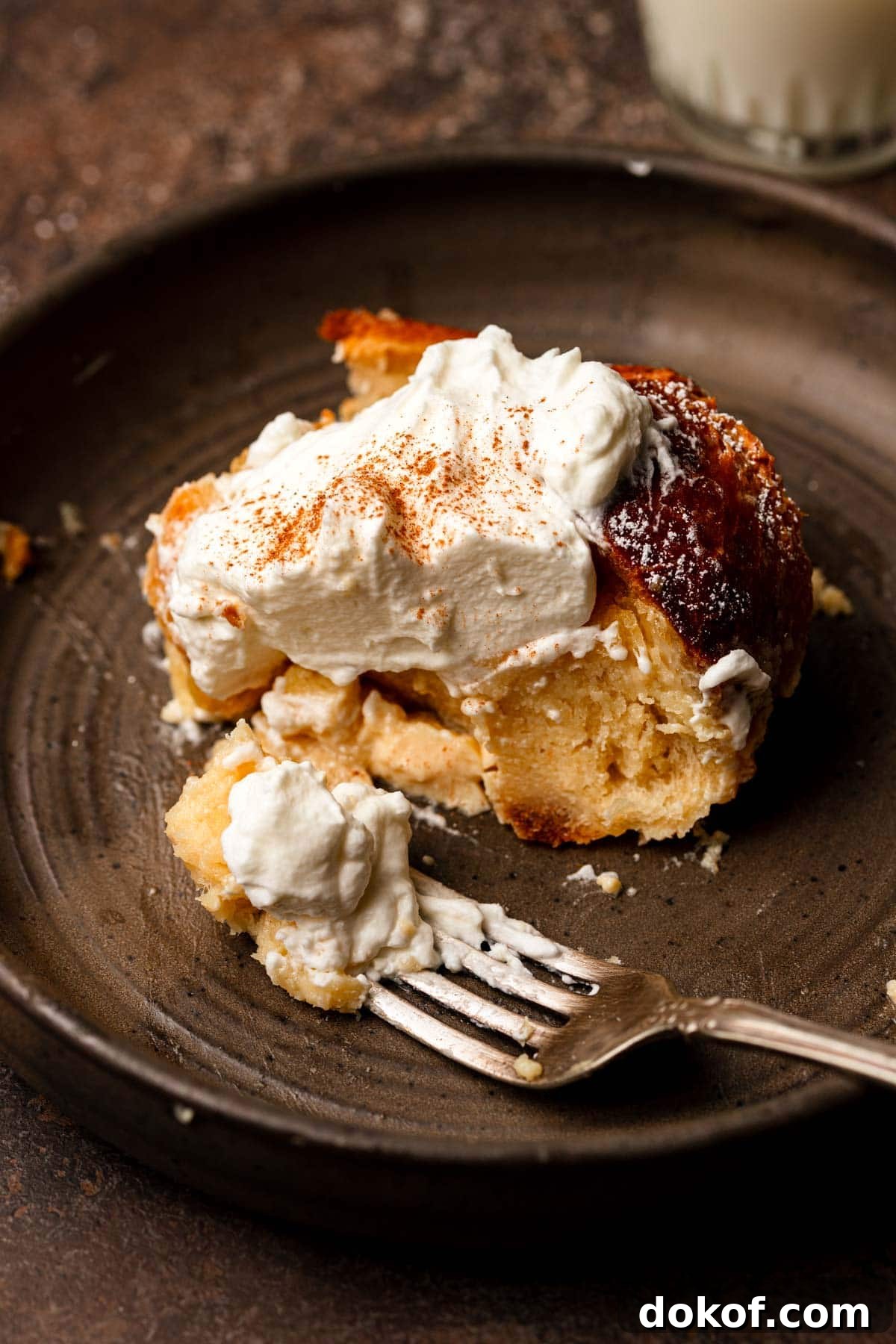 A slice of bread pudding topped with cream and a dust of cinnamon.