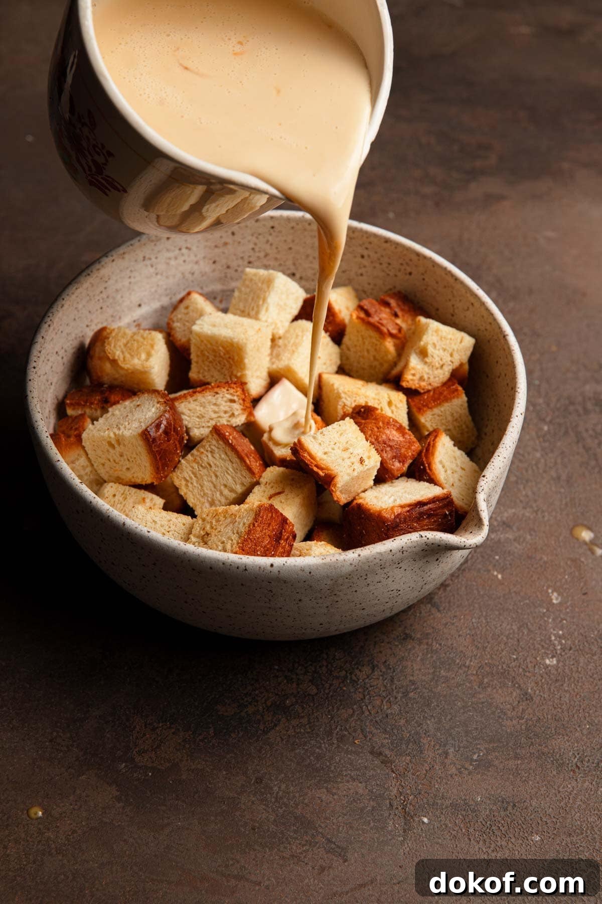 Pouring custard over bread cubes.