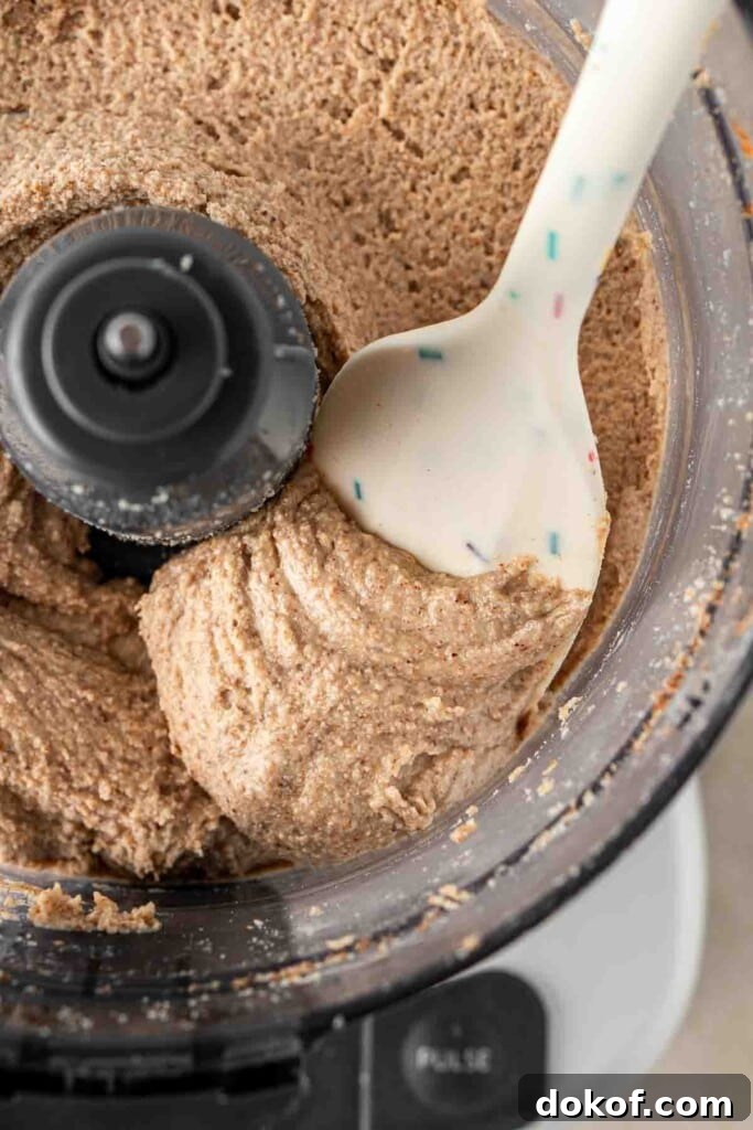 Homemade Almond Butter: Simple Recipe for Smooth, Creamy Spread 9 A spatula scooping almond butter from the food processor.