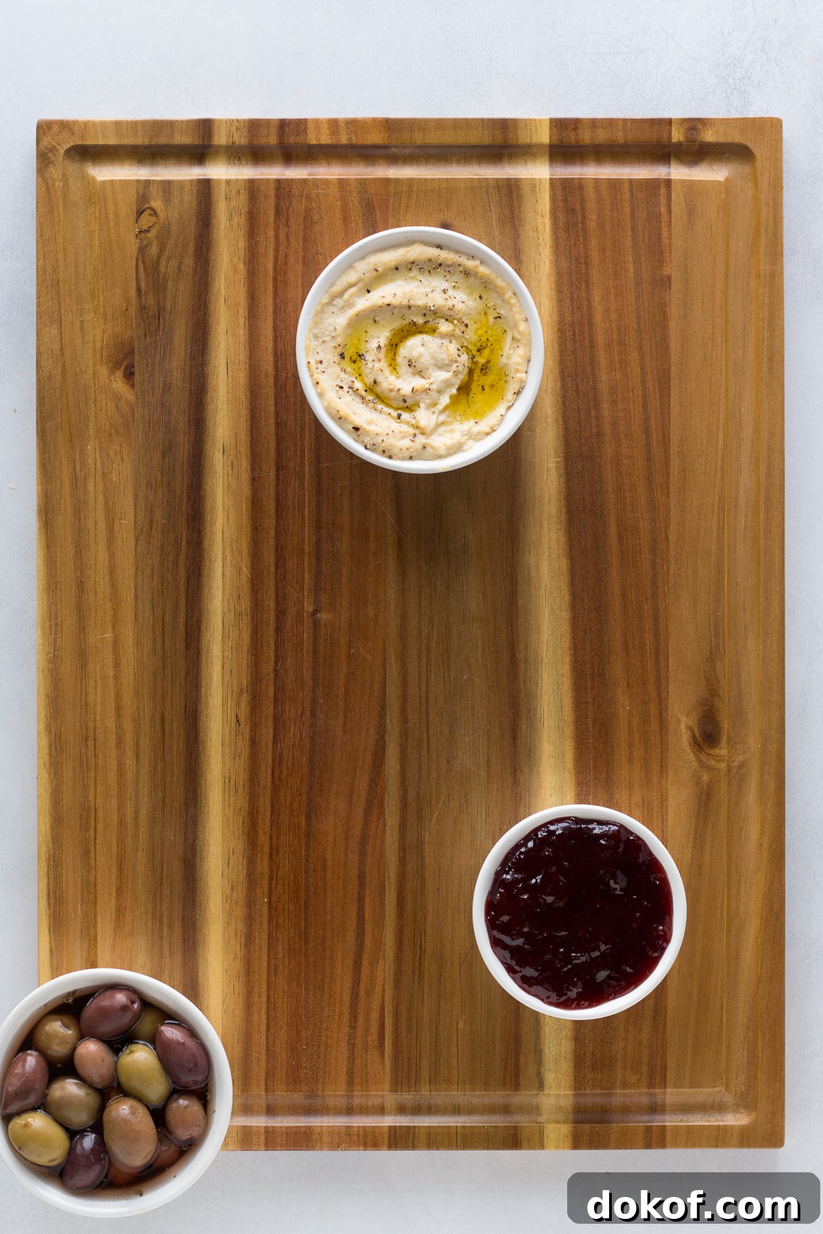 vegan board with hummus, olives, and jam on wooden board by Flora & Vino