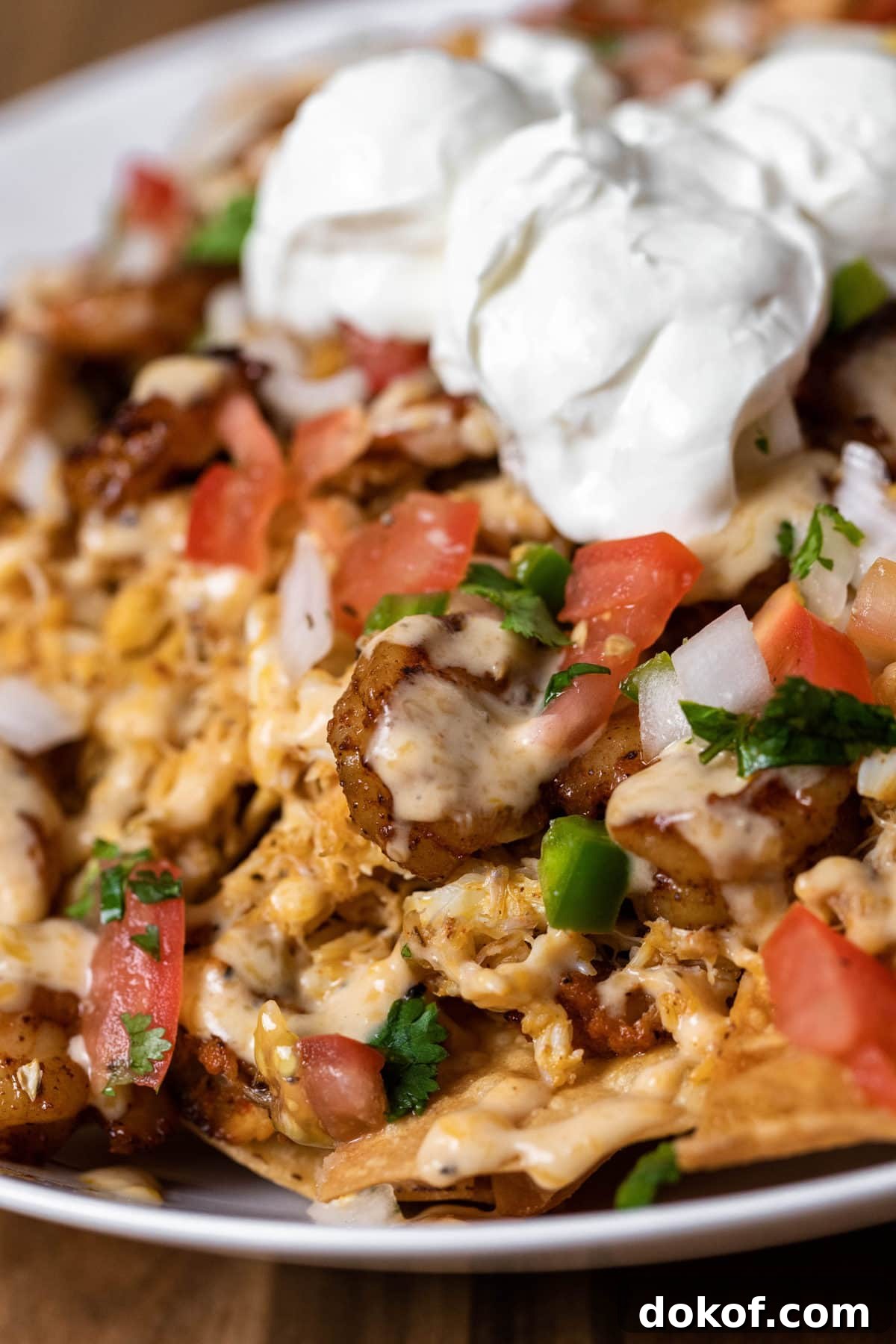 plate of seafood nachos topped with pico de gallo, sour cream and cilantro