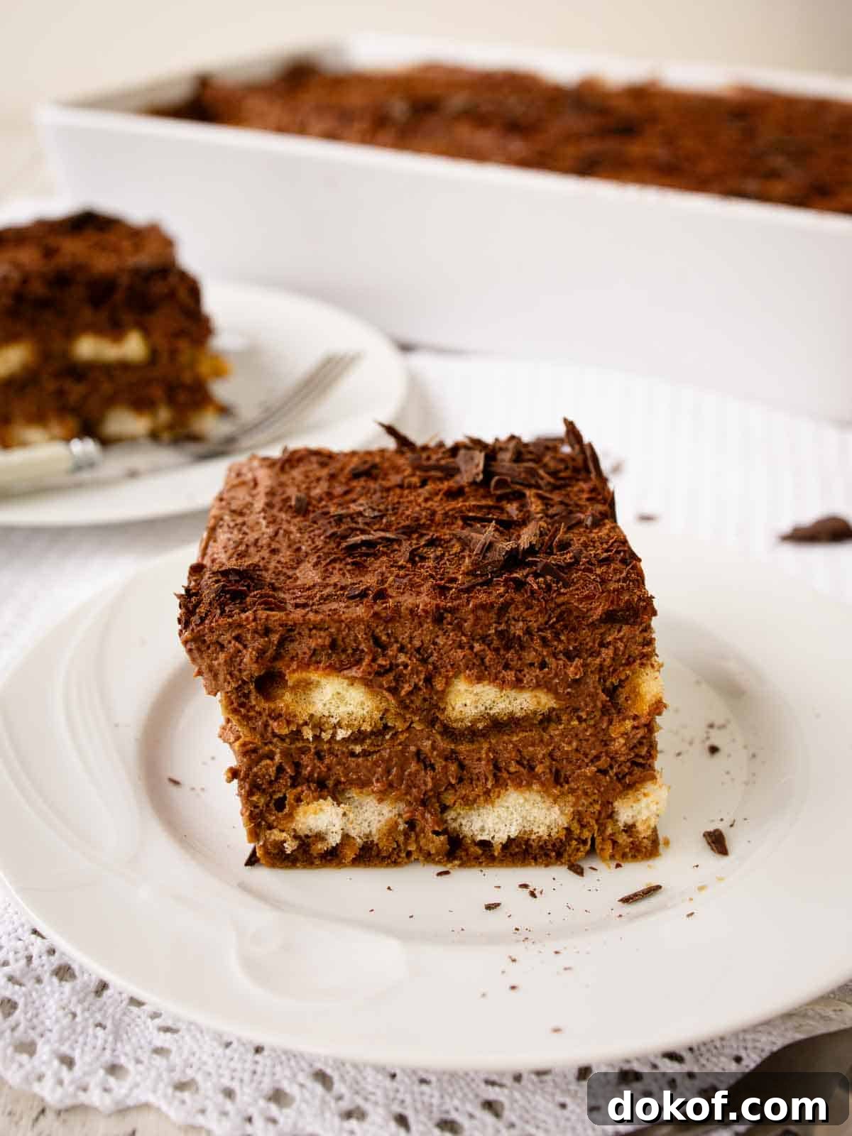Decadent Chocolate Tiramisu Recipe for Coffee Lovers 2 Large square piece of Chocolate Tiramisu on a white plate.
