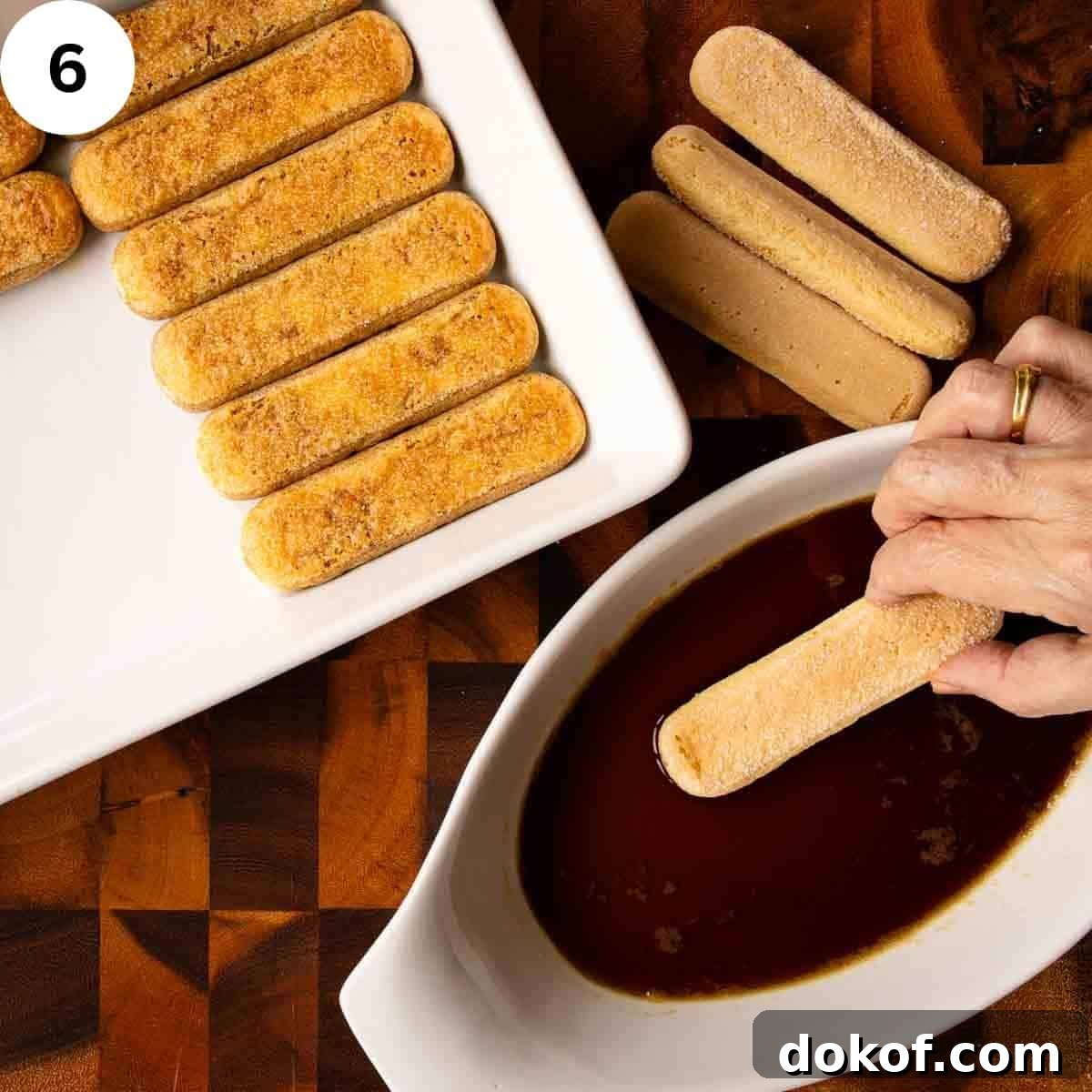 Decadent Chocolate Tiramisu Recipe for Coffee Lovers 9 Savoiardi cookie being dipped in dark liquid with more in a white baking dish.