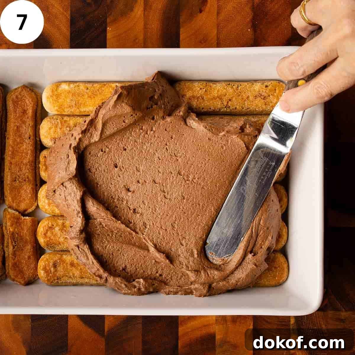 Decadent Chocolate Tiramisu Recipe for Coffee Lovers 10 Chocolate cream being spread over savoiardi cookies.