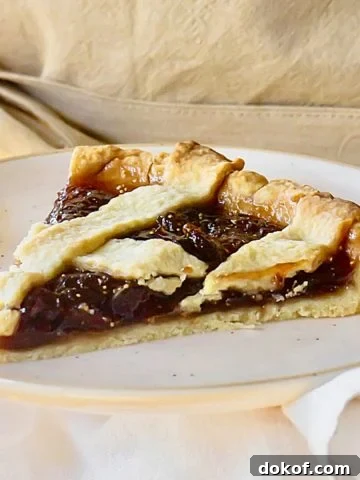 Single slice of lattice fig jam tart on a plate. Beige background.