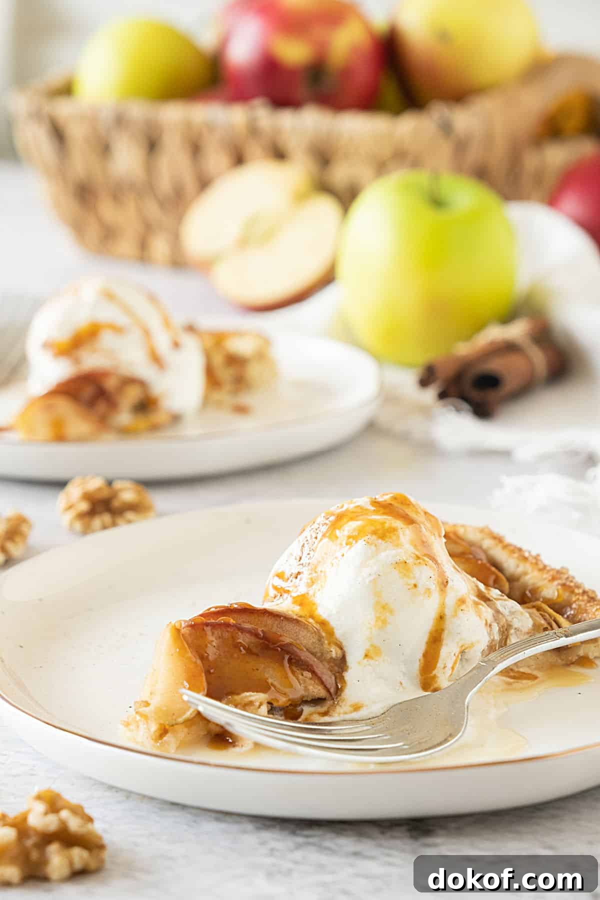 Rustic Apple Galette Recipe: Simple Homemade Apple Tart 3 White plates with caramel apple galette slice with ice cream. Basket of apple in the background. Light grey surface.