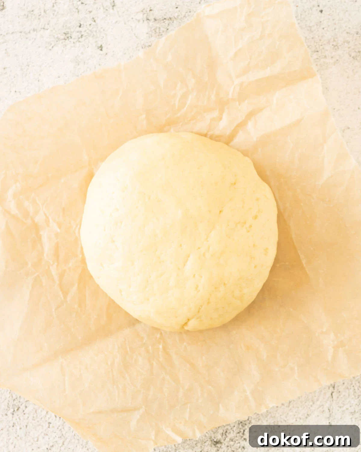 Rustic Apple Galette Recipe: Simple Homemade Apple Tart 5 Round ball of pie crust on a beige paper on a light grey surface.