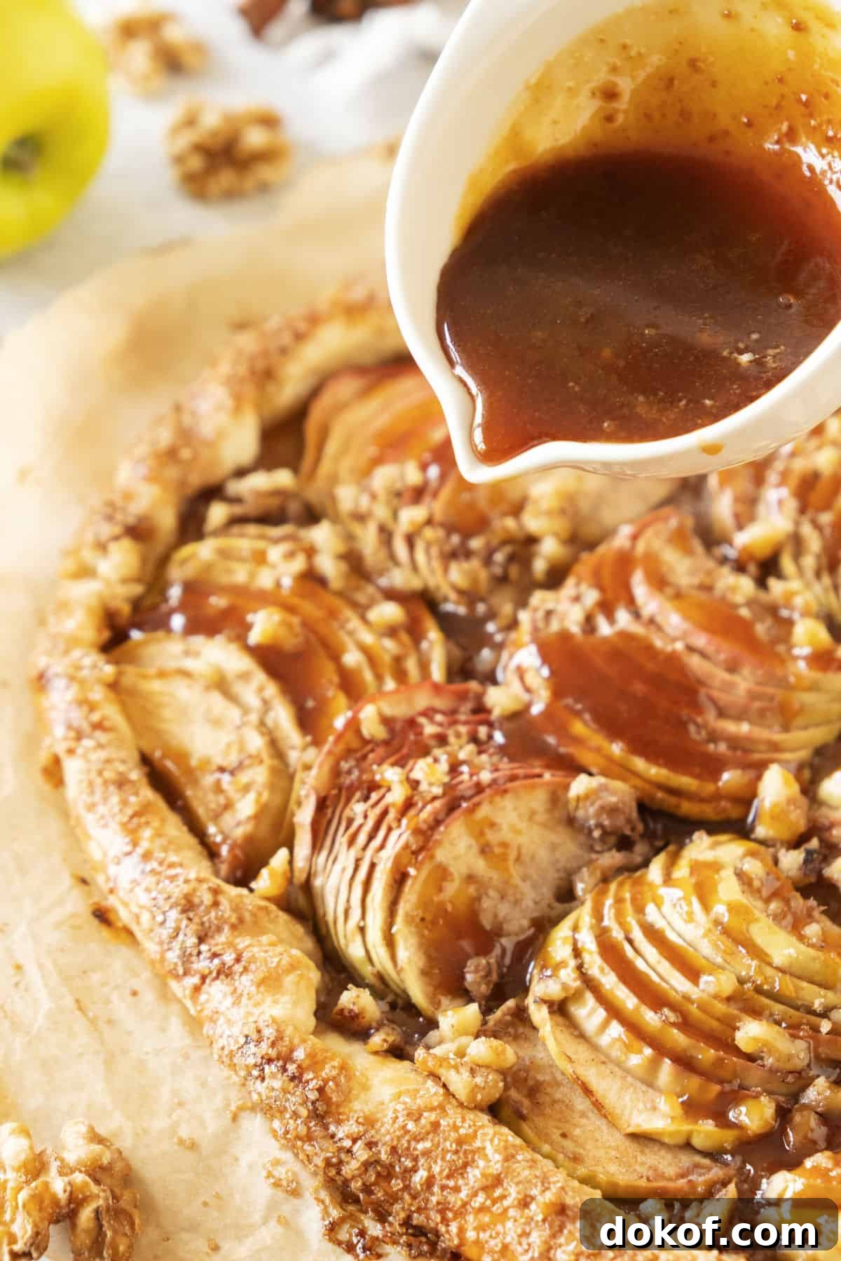 Rustic Apple Galette Recipe: Simple Homemade Apple Tart 10 Pouring caramel on a baked apple galette on a beige parchment paper.