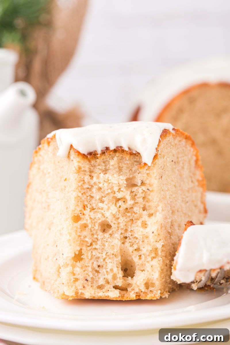 bite of eggnog bundt cake on a fork next to the slice on a dessert plate