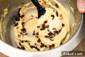 Raisins being added to the cupcake mixture and folded into the mix using a silicone spoon