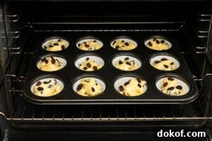 A cupcake tray filled with queen cake mixture going in the oven