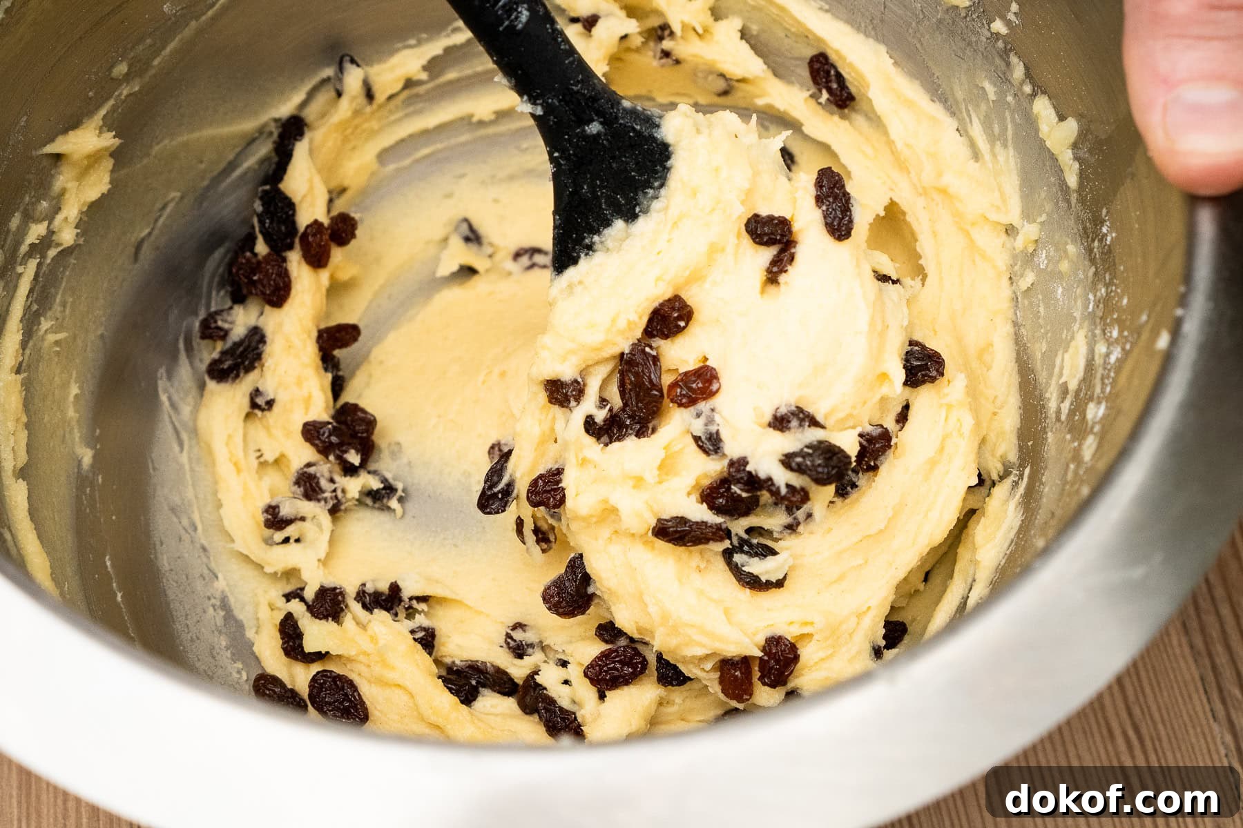 Raisins being added to the cupcake mixture and folded into the mix using a silicone spoon