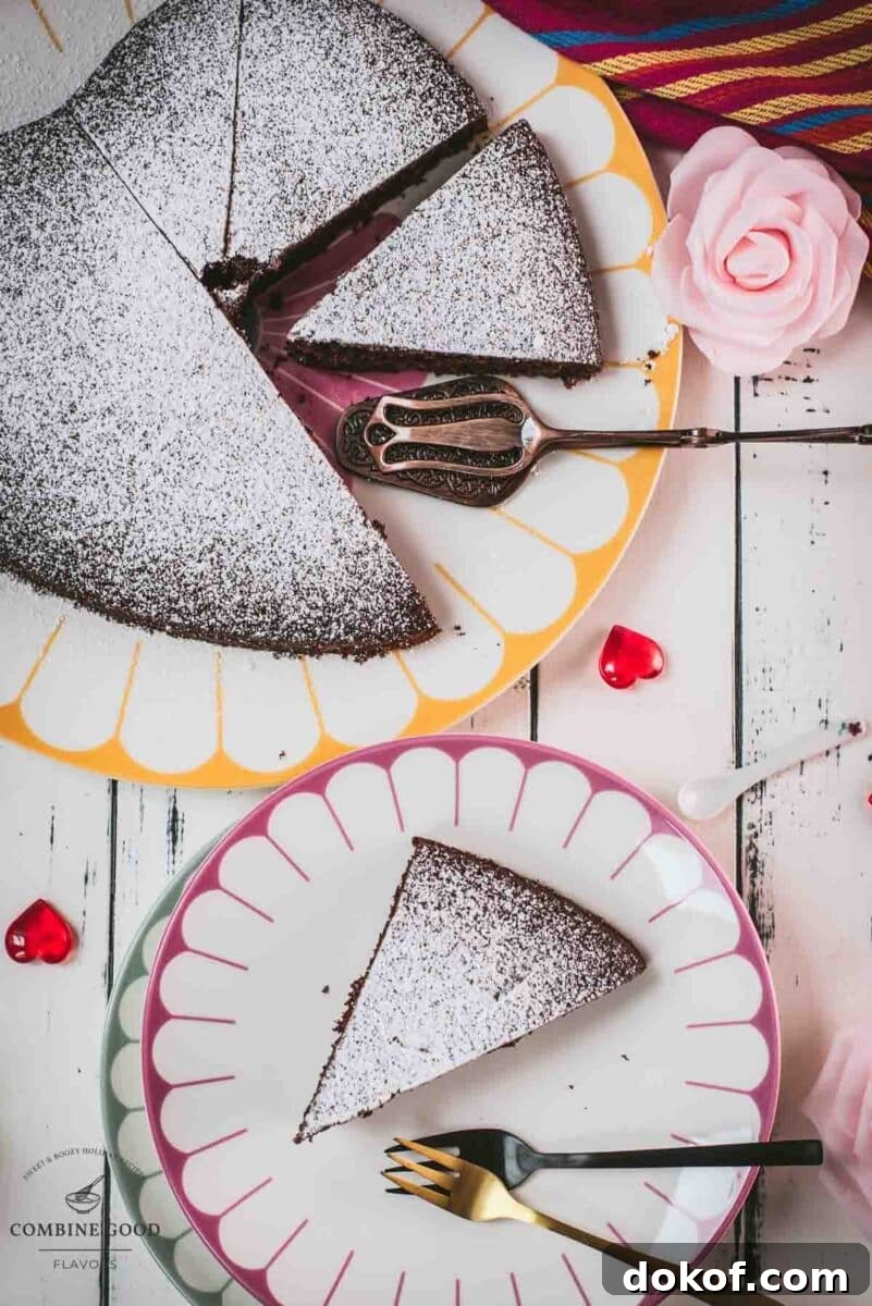 Delicious heart-shaped chocolate cake, dusted with powdered sugar. Ideal for Valentine's day! Placed on yellow-white serving plate.