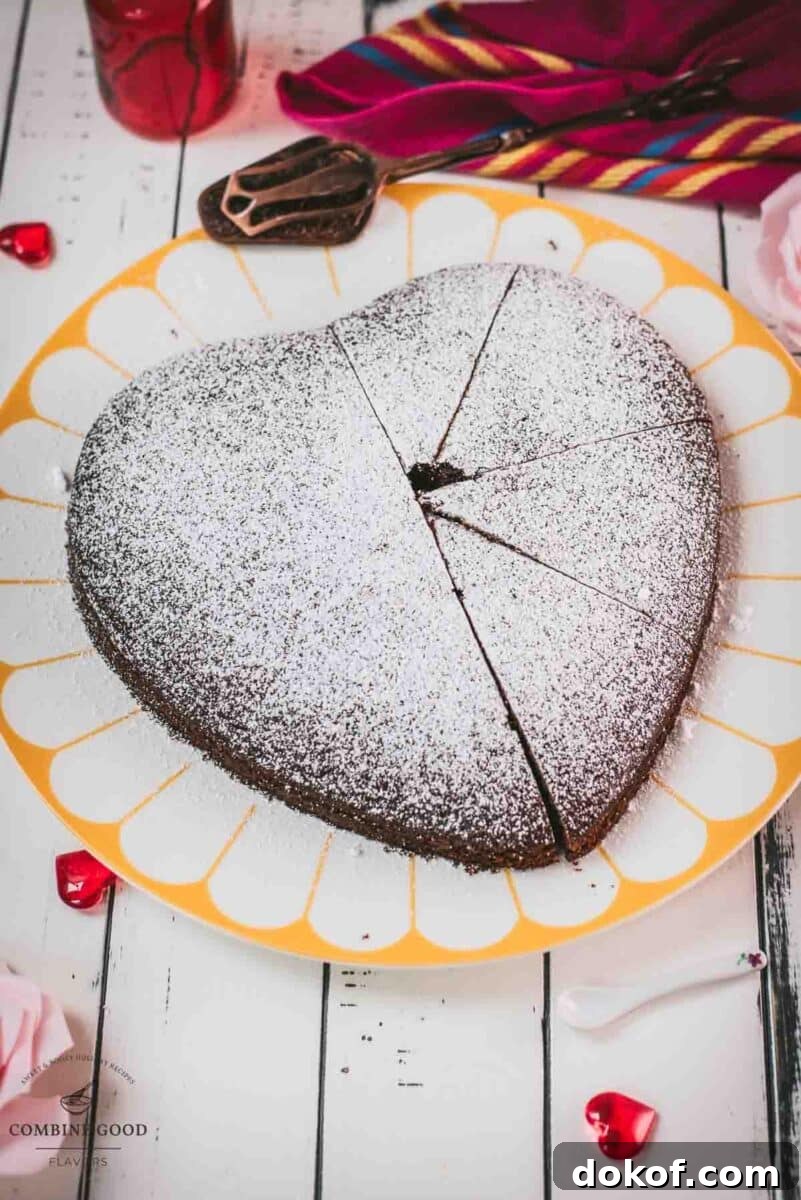 Delicious heart-shaped chocolate cake, dusted with powdered sugar. Ideal for Valentine's day! Placed on yellow-white serving plate.