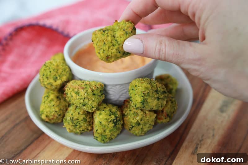 keto broccoli tots on a white plate with a white bowl of sriracha dipping sauce 