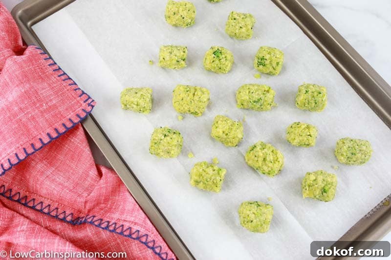 low carb broccoli tots on parchment paper and baking sheet with a pink towel on the side 