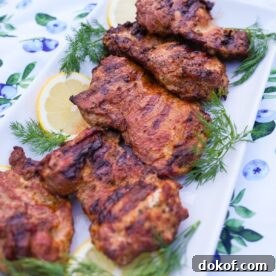 Lemon garlic chicken on a plate with dill and lemon garnish.