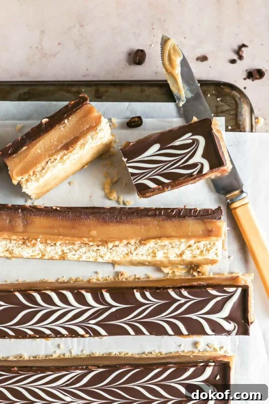 Espresso millionaire shortbread bars cut into long strips on a sheet of parchment paper on a cookies rack with a knife.