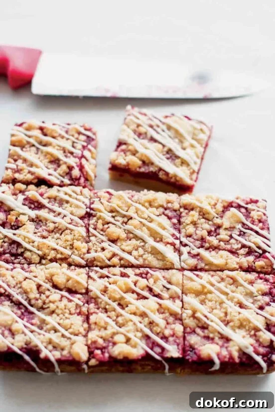 A batch of raspberry Linzer bars cut into nine squares, with one square missing and a knife in the background.