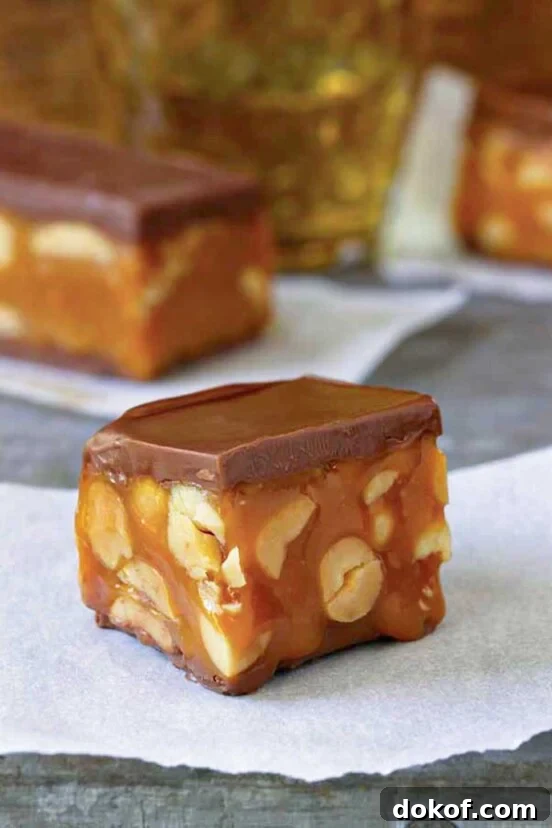 A square piece of homemade snickers bar on a piece of parchment.