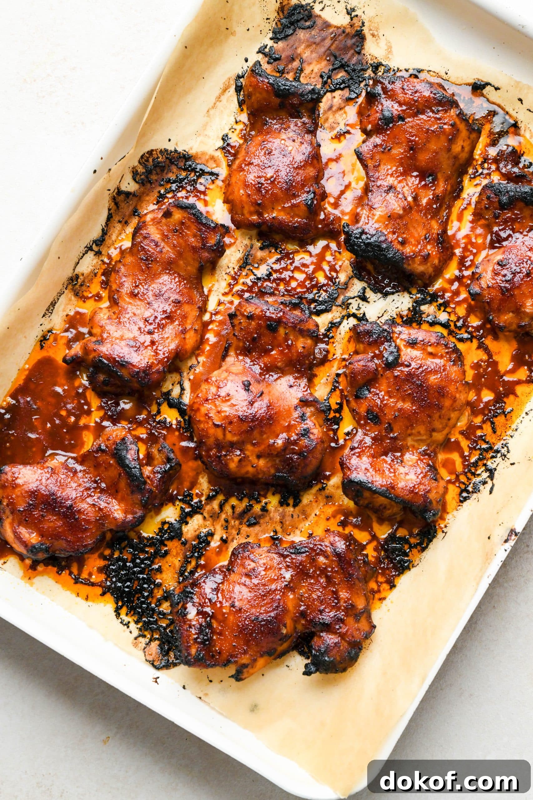 Oven-Baked Caramelized BBQ Chicken Thighs with Sticky Glaze 12 How to make BBQ Chicken Thighs in the Oven: Saucy chicken thighs on a baking sheet with caramelized edges.